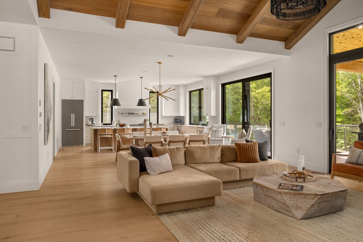 Open great room, dining area and kitchen under the vaulted wood ceiling