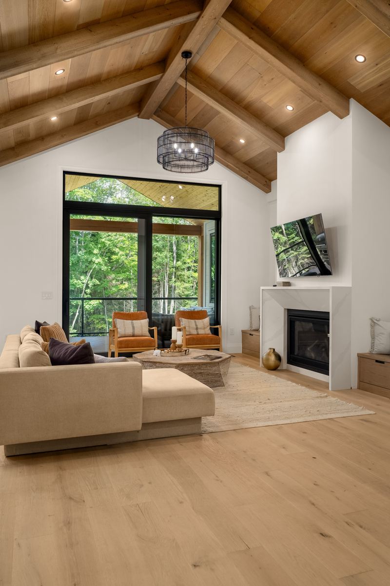 Great room with a vaulted wood ceiling, gas fireplace and black-framed windows
