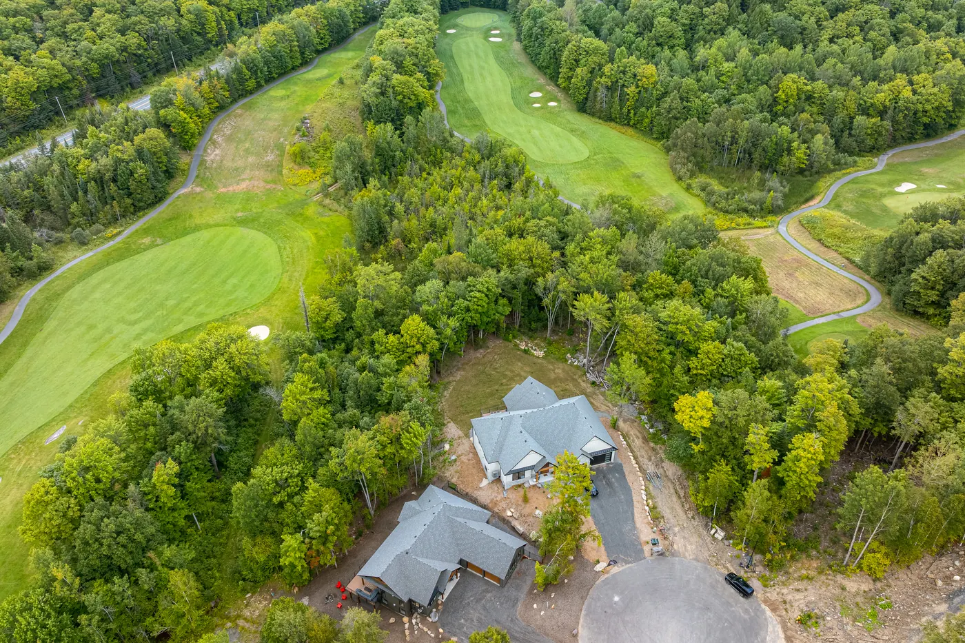 Aerial view of two finished homes at the Glen Eagle Court turnaround, set between two fairways at Deerhurst Highlands