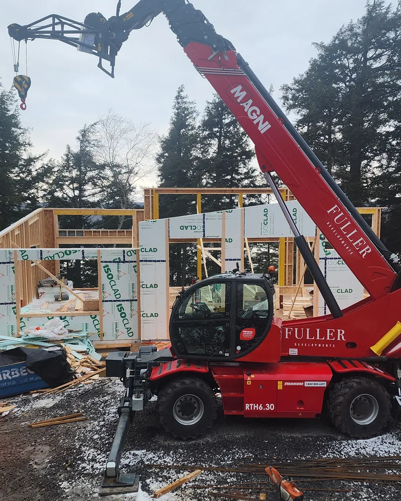 Fuller Developments Magni RTH 6.30 rotating telehandler working alongside a framed custom home