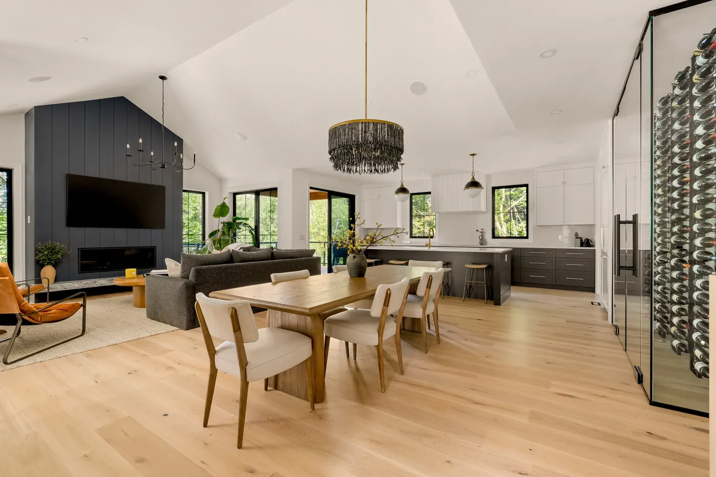 Vaulted great room, dining table, kitchen island and glass wine wall in the Fuller model home