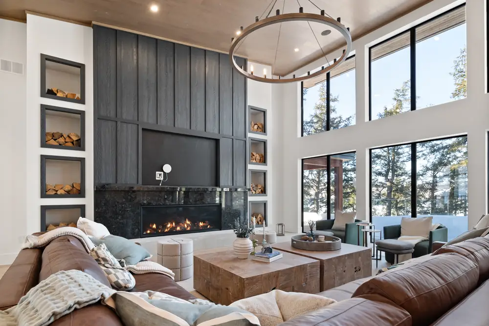 Great room at Hemlock Point with a black stone fireplace, dark panelled wall and windows to the lake